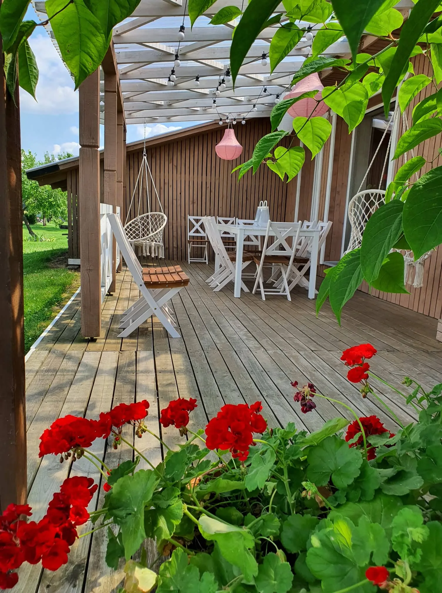 Pirties terasa su pelargonijomis ir supamuoju suolu